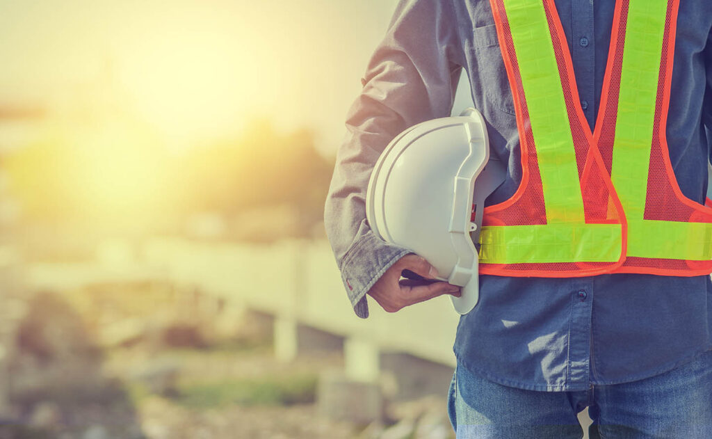 construction supervisor wearing a safety vest and holding a white hardhat