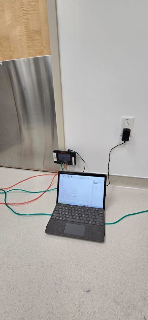 A laptop sitting on the floor next to a BSL-3 lab door